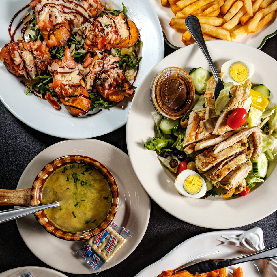 An overhead view of Beto's Italian dishes, including bruschetta, chicken salad, soup, and french fries.