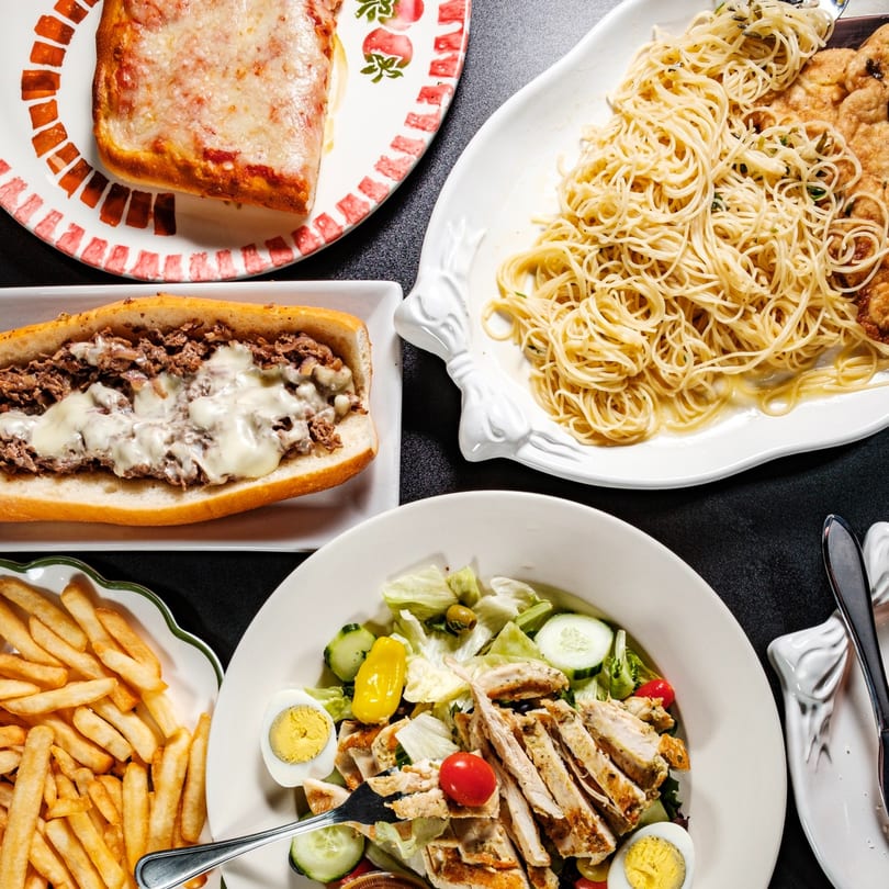 A feast of Beto's Italian dishes: pizza, cheesesteak, spaghetti, chicken salad, and fries.